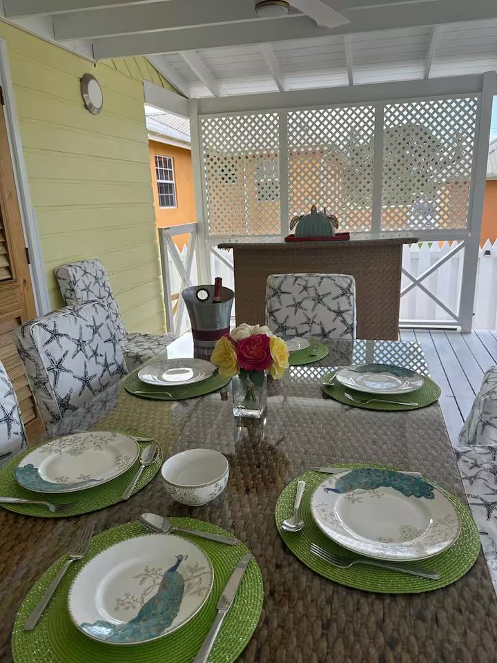Covered dining verandah — place settings with peacock plates, fresh roses and a wine bucket