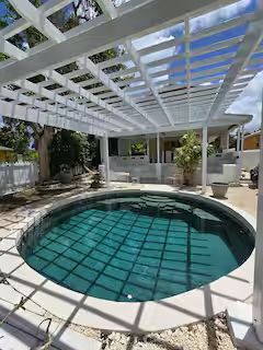 Lime Cottage pool — circular pool under a white pergola, deep teal water